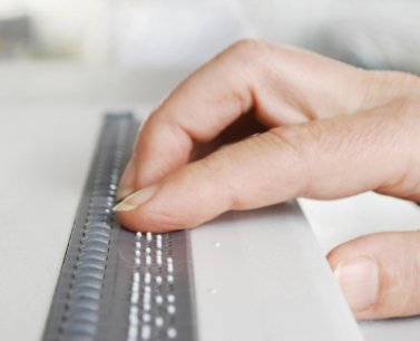 zeigt eine Hand auf einer Brailletastatur 